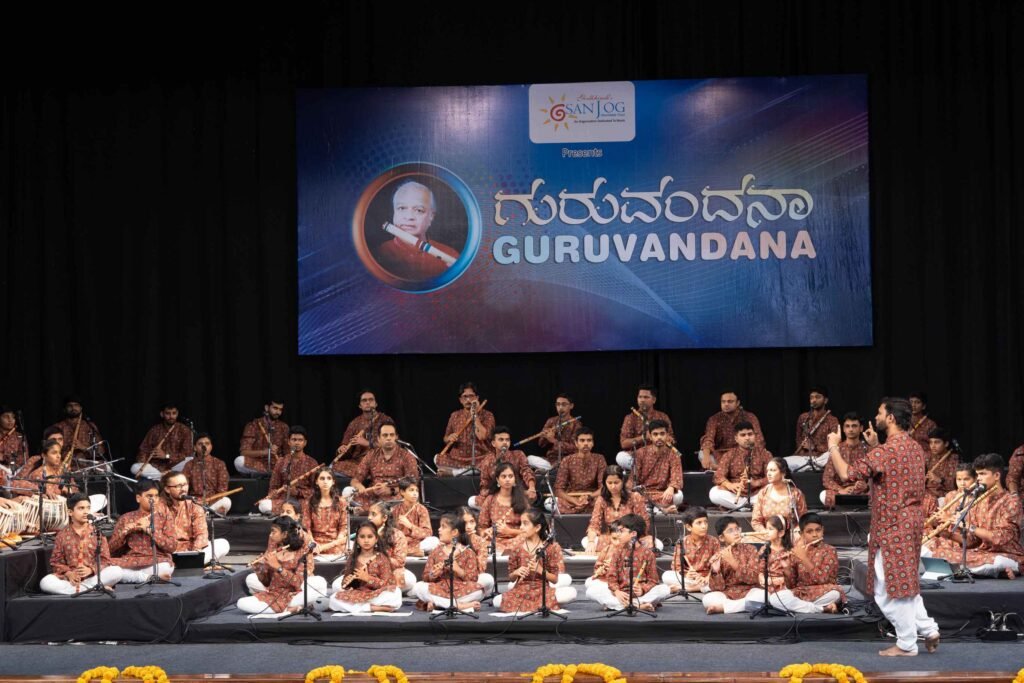 Students performing in a large bansuri ensemble on stage